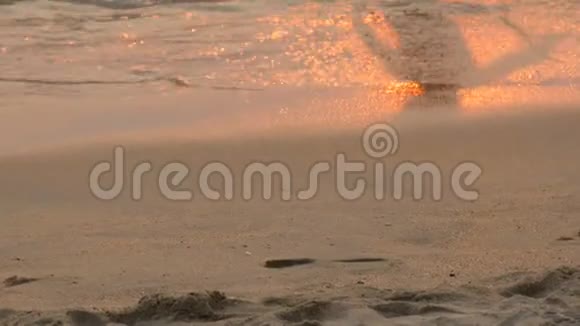 夕阳西下时一个孩子在海上海岸背景上玩耍的剪影在这片背景上夕阳的红光视频的预览图