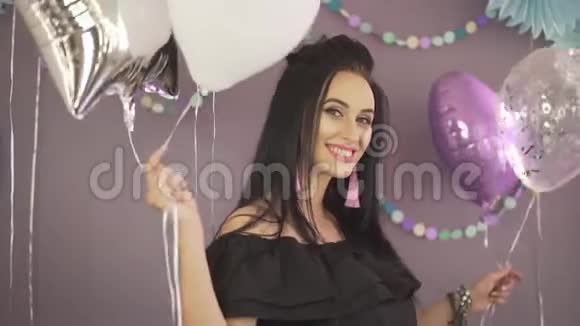 美丽迷人的深褐色头发的年轻女子手里拿着五颜六色的气球享受着派对庆祝的气氛视频的预览图