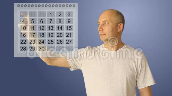 年轻的秃头用虚拟日历工作男性选择开始和结束两个日期为休息或视频的预览图
