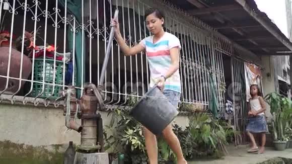 漂亮的女士用手握着水泵从深井里抽水视频的预览图