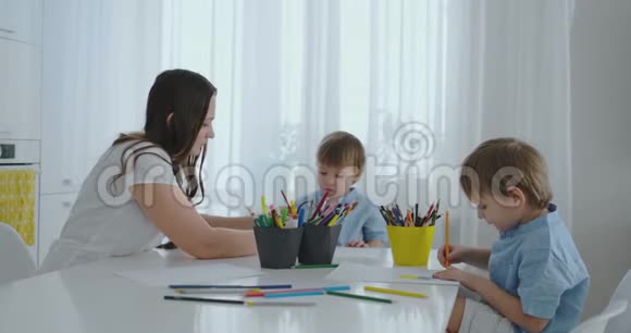 妈妈帮儿子学画做作业学前准备在家坐在白色厨房视频的预览图