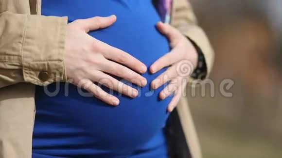 穿着蓝色衬衫的女孩带着母亲的温柔亲切地照顾着她的大肚子和孩子稳定的凸轮慢的莫视频的预览图