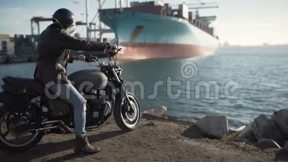 摩托车手坐在一辆老咖啡馆里的摩托车上港口背景视频的预览图