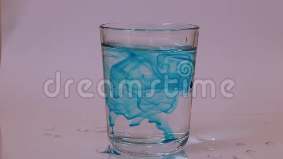 蓝色的水在玻璃里把干冰放在里面在白色的背景上产生白色的烟雾视频的预览图