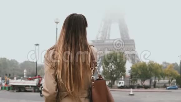 法国巴黎埃菲尔铁塔附近一位年轻美丽的女士在雾蒙蒙的早晨散步用手机交谈视频的预览图