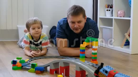 家庭观念男孩和爸爸在木地板上玩火车父亲与儿子视频的预览图