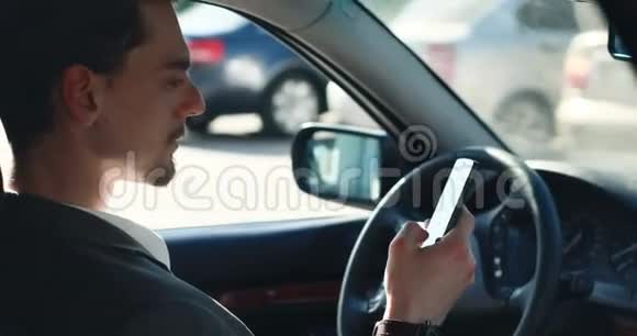 穿着昂贵的时髦车坐着在停车场上使用智能手机这是一个颇具攻击性的英俊商人视频的预览图