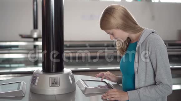 美丽的女人在机场航站楼附近的充电器使用触摸屏搜索信息视频的预览图