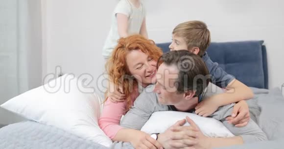 幸福的微笑家庭在卧室里玩得开心早上躺在床上视频的预览图