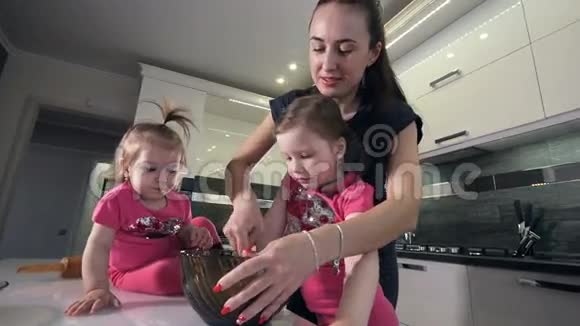 母亲和两个女儿的慢镜头把面团混合在一起肖像高清视频的预览图