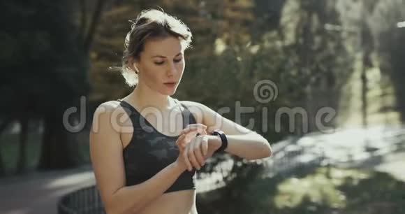 使用智能手表的无线耳机和晨曦运行的健身妇女视频的预览图