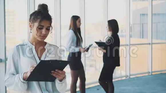 一位身穿白色西装手里拿着文件夹的年轻商务女性视频的预览图