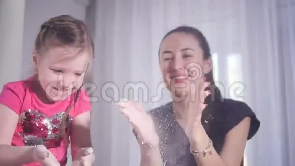 母亲和女儿玩面粉的慢动作拍摄肖像特写镜头高清视频的预览图