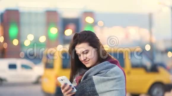 迷人的棕色头发峡谷美丽的女孩使用白色电话在城市的街道在春天没有聚焦的光线视频的预览图