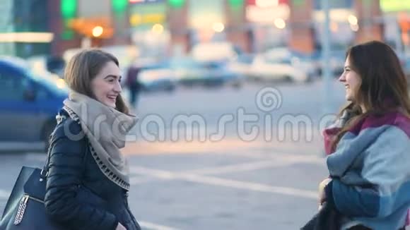 两个迷人的年轻女孩在城市的街道上和欢笑等待着一个人稳定的凸轮慢镜头视频的预览图