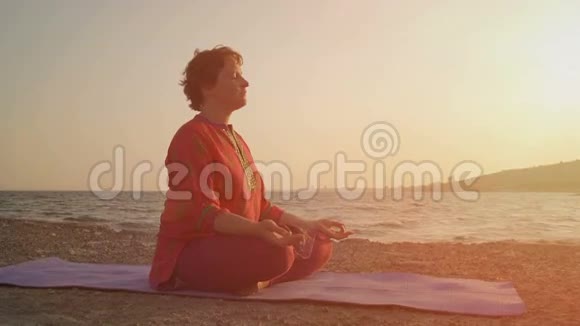 女人在夕阳下沉思莲花的姿势瑜伽冥想的概念视频的预览图