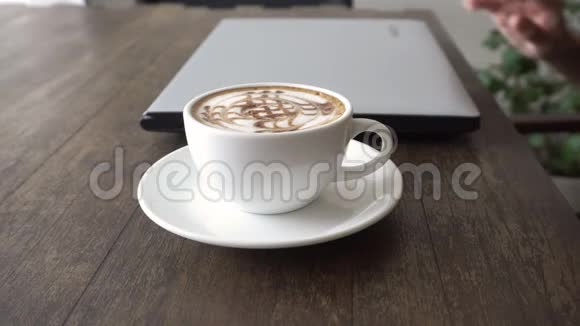 年轻女性在客房咖啡馆餐厅家庭或办公室使用笔记本电脑并配有一杯白色咖啡视频的预览图