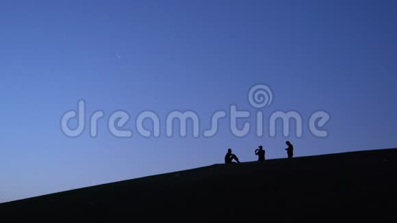三名男子在智能手机上拍照清晨在山坡上与杨自拍的剪影视频的预览图