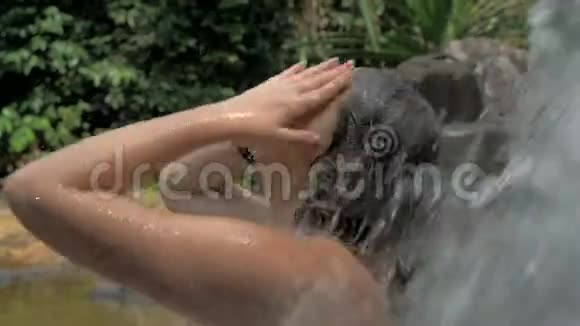 热带天堂的性感女人站在瀑布下在热带地区惊人的瀑布里度假视频的预览图