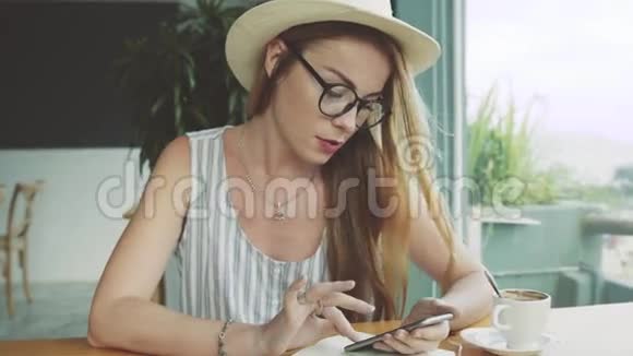 美丽的年轻女性使用手机进行教育严肃的女人在咖啡馆里使用智能手机视频的预览图