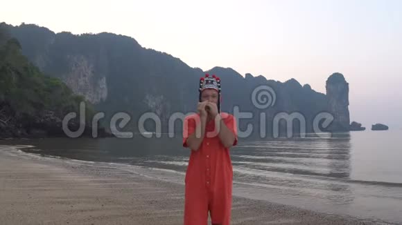 在泰国海岸线上的黄昏时分戴着传统泰国女帽的古怪的白种人用竖琴演奏视频的预览图