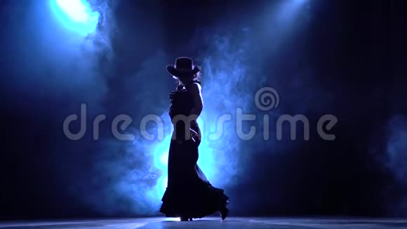 穿着别致裙子的女人会跳一支燃烧的舞蹈从后面发光烟雾背景剪影慢动作视频的预览图
