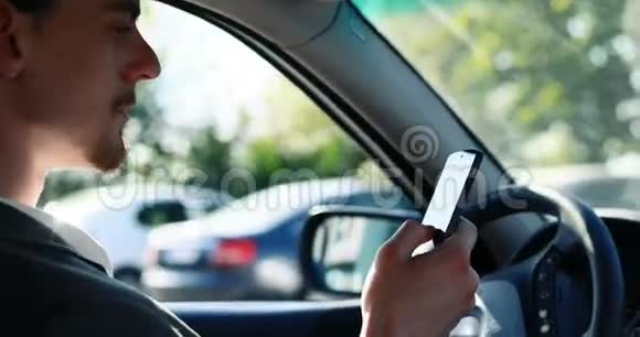年轻聪明有魅力的商人在汽车上使用智能手机城市背景视频的预览图