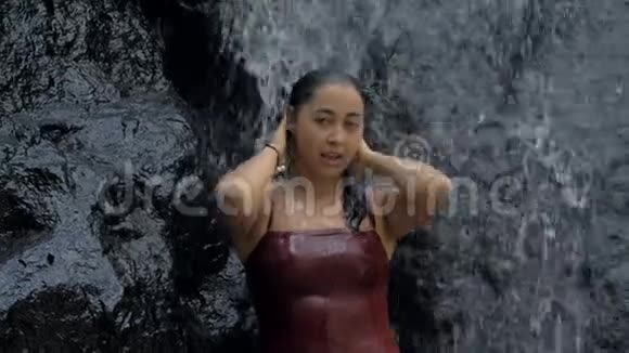 热带天堂的性感女人站在瀑布下在热带地区惊人的瀑布里度假视频的预览图