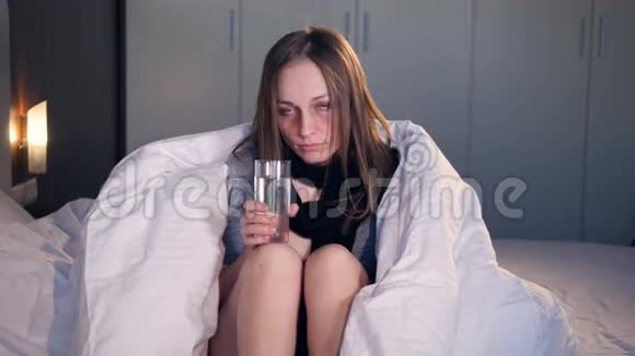 生病的女人坐在床上喝水4K视频的预览图