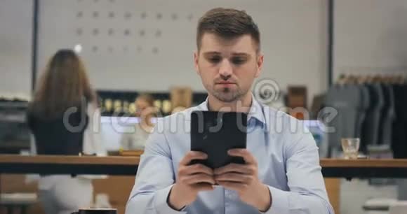 聪明的年轻商人律师医生经理办公室工作人员在咖啡馆的午餐时间使用他的平板电脑视频的预览图