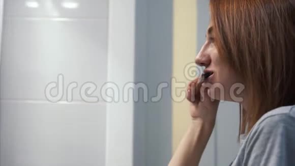 在浴室里刷牙的漂亮年轻女人视频的预览图