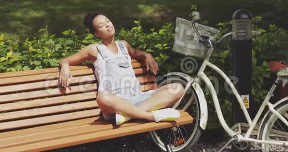 在公园长椅上享受阳光的女人视频的预览图