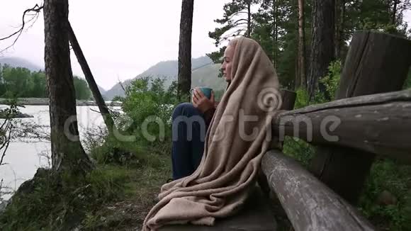 年轻女子在河边喝热咖啡或茶在山区度假胜地平静舒适的时光视频的预览图