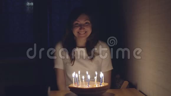 年轻女子在节日蛋糕上吹蜡烛视频的预览图