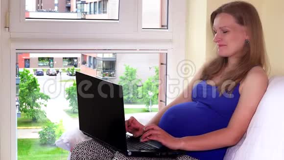 微笑未来的母亲用电脑坐在窗边视频的预览图
