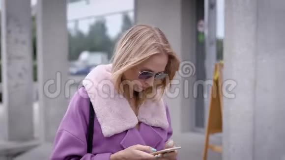 时尚女性在街上使用智能手机视频的预览图