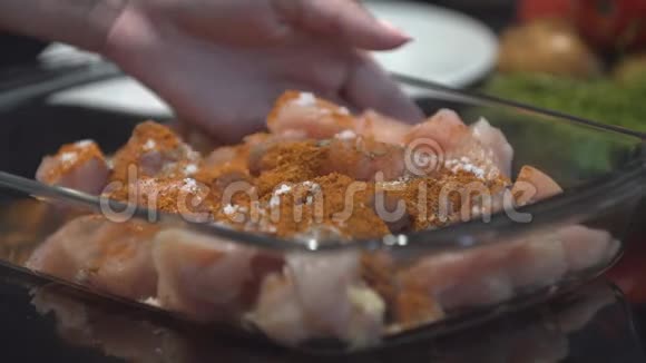 厨师用手将生鸡肉和咖喱香料混合在烤盘上视频的预览图