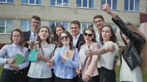学校背景上的快乐学生举起手指展示成功和良好的心情视频的预览图