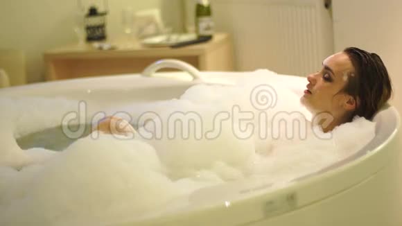 漂亮的年轻女子在热水浴缸里泡澡放松视频的预览图