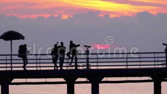 日落时海上码头上的人剪影视频的预览图