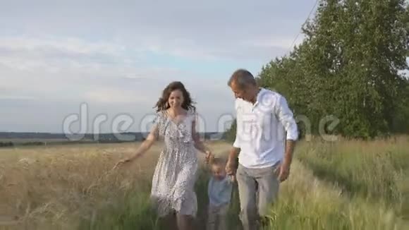 妈妈爸爸和小儿子一起在户外幸福的家庭跑到镜头前视频的预览图