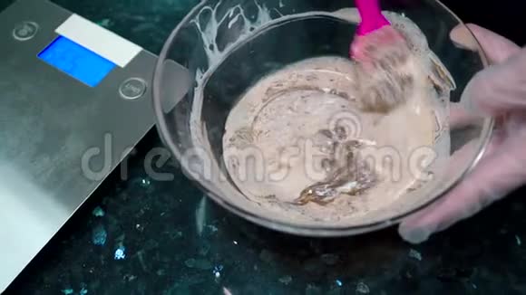 一个戴手套的糖果师把巧克力奶油揉进碗里视频的预览图