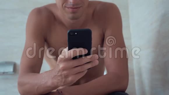 年轻人用智能手机坐在家里的厕所里坐在马桶里拿电话的人视频的预览图