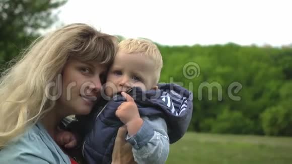 快乐的年轻金发母亲抱着她的孩子在公园玩耍视频的预览图
