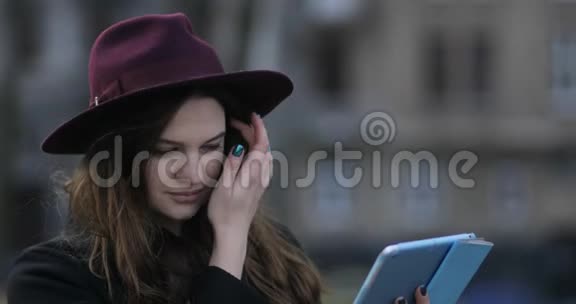年轻笑容可掬的欧洲现代黑人女士带着她的智能手机里使用平板电脑4k视频的预览图