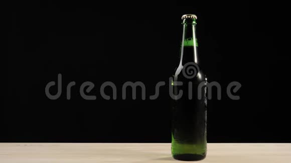 新鲜啤酒手把一个棕色的瓶子和美味的工艺啤酒放在绿色瓶子附近啤酒放进木桌里视频的预览图