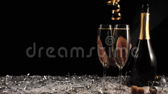 好香槟酒两杯香槟和一瓶黑色背景配有起泡葡萄酒的长笛手拿杯子视频的预览图
