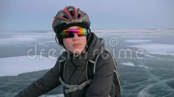 人是站在冰上的自行车他看着美丽的日落骑自行车的人穿着灰色的羽绒服背包视频的预览图