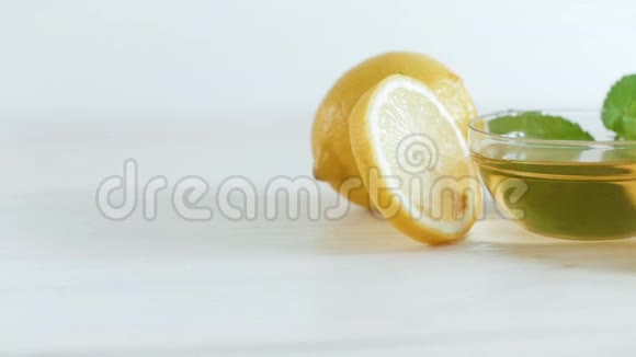白色木桌上的天然蜂蜂蜜薄荷和黄色柠檬的特写慢镜头视频的预览图