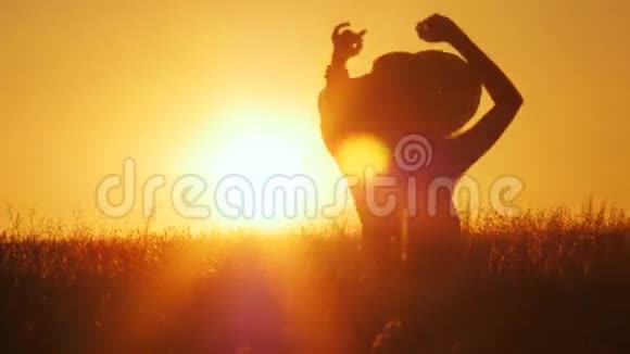 迷人的年轻女子剪影在日出时在户外跳舞太阳在她身后的地平线上闪闪发光4k次视频的预览图